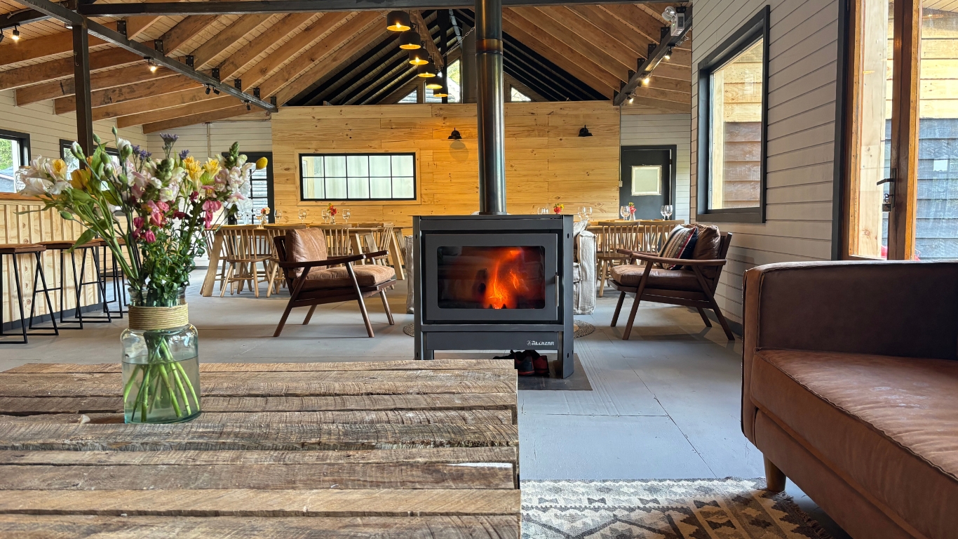 Interior del Patagonia Bikers Lodge, con estufa a leña, sillones y el comedor