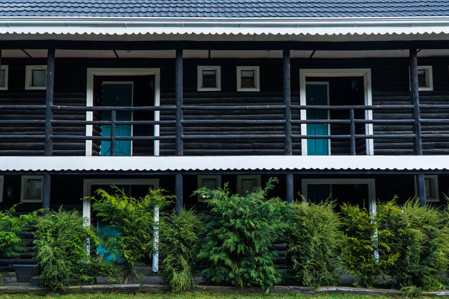 Edificio de las suites del lodge, de madera oscura, rodeado de jardín