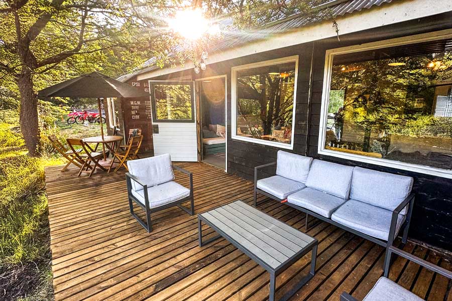 Terraza de madera del lodge con sillones y mesa al aire libre