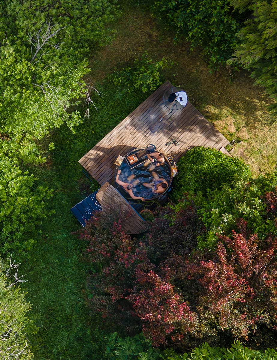 Vista aérea de la tinaja caliente del lodge sobre una terraza de madera, rodeada de vegetación